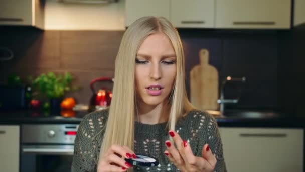 Ung vlogger pratar om smink rouge för ansikte. Attraktiv ung kvinna talar om kosmetisk rouge för ansiktet medan du spelar in video för skönhet vlog i köket. — Stockvideo