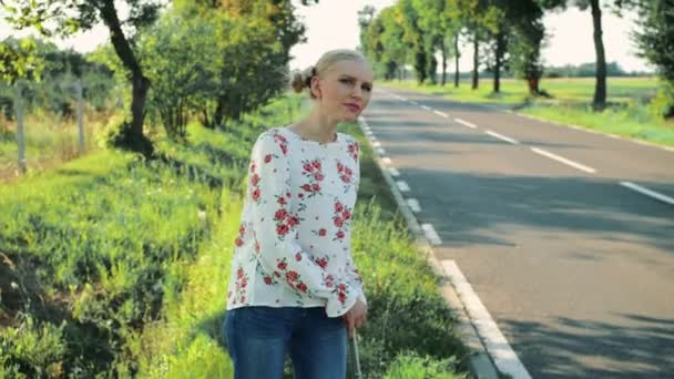 Utazó fiatal nő stoppolás vidéki úton. — Stock videók
