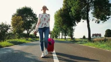 Yolda yürürken bavul ile neşeli genç kadın.