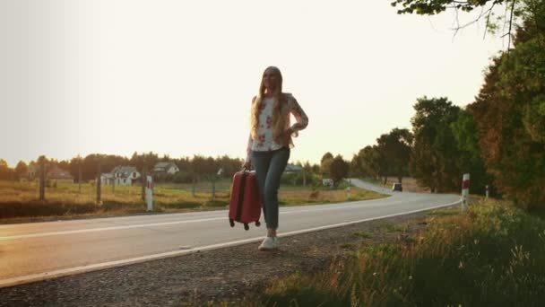 Веселая женщина с чемоданом идет по дороге . — стоковое видео