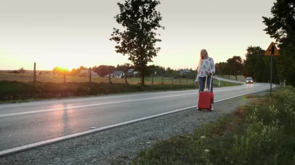 Молода жінка автостопом по сільській дорозі . — стокове відео