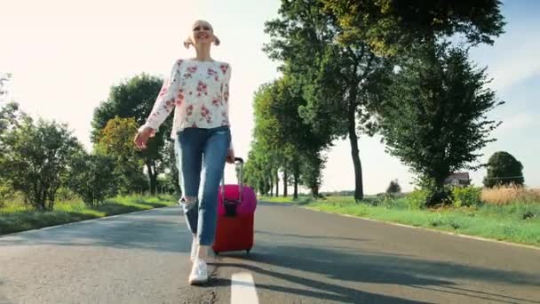 Jovencita alegre con maleta caminando por el camino . — Vídeo de stock