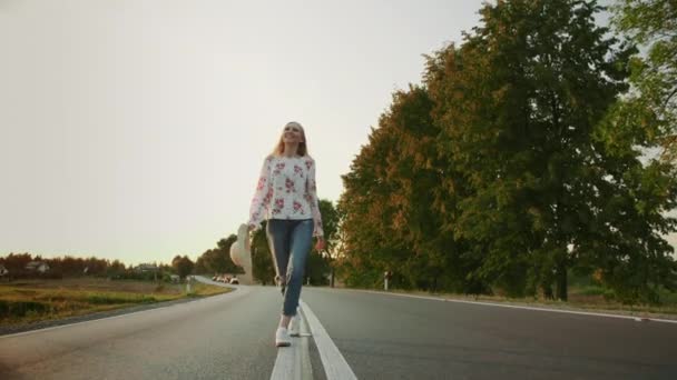 Mujer con sombrero corriendo por la carretera . — Vídeos de Stock