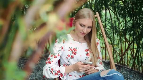 Młoda kobieta za pomocą smartfona w altanie roślin. — Wideo stockowe