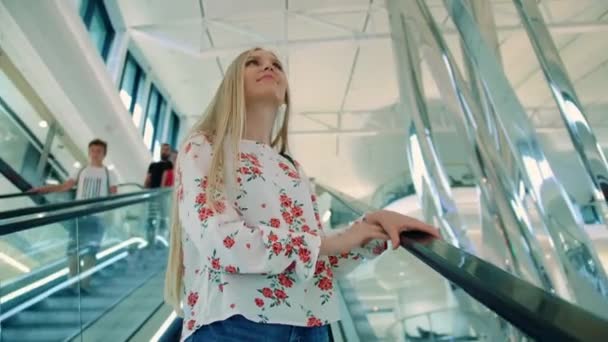 妇女在商场乘自动扶梯。 在欧洲现代购物中心，从下面拍摄到一位可爱的年轻女士骑着楼梯往上看. — 图库视频影像