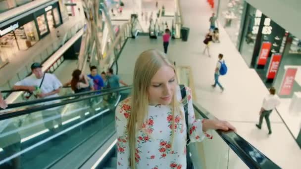 Жінка їде на ескалаторі в торговому центрі. Знизу на сходах сучасного торгового центру в Азії дивилася вродлива молода леді.. — стокове відео