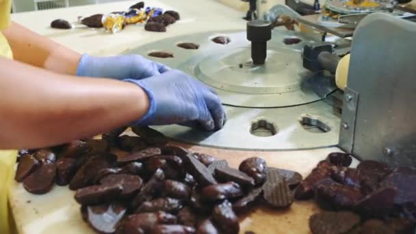 Ruce k nepoznání zaměstnankyně uvedení čokoládové bonbóny do balicí stroj v cukrářské výrobě. — Stock video