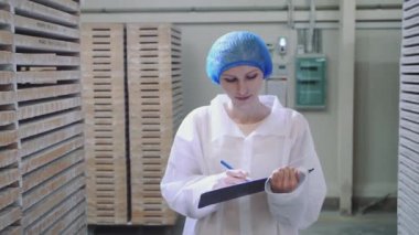 Denetleyici fabrika deposunu kontrol ediyor.