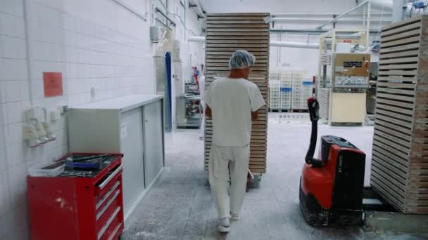 Tovární dělník tlačí vozík s bonbóny ve skladu. — Stock video