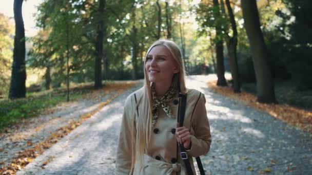 Hermosa joven rubia caminando en el parque en otoño — Vídeos de Stock