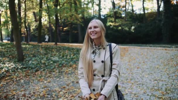Jong meisje wandelen in de herfst park en gooien gouden bladeren in de lucht, slow motion — Stockvideo