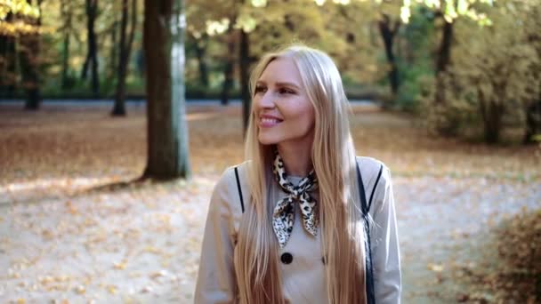 Bela jovem loira caminhando no parque no outono — Vídeo de Stock