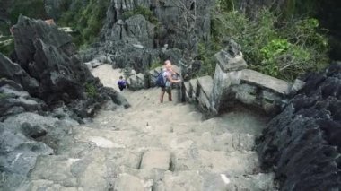 Şık kadın merdivenlerden aşağı yürüyüş ve Hang mua Peak kamera bakarken elini sallayarak, Ninh Binh, Vietnam.