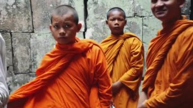 Genç Budist Keşişler tapınağa Saffron cübbesiyle girip Angkor Wat 'a bakıyorlar..