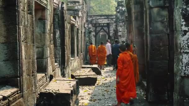 サフラン・ローブの寺院を歩く若い仏教僧とアンコールワットを見下ろす. — ストック動画
