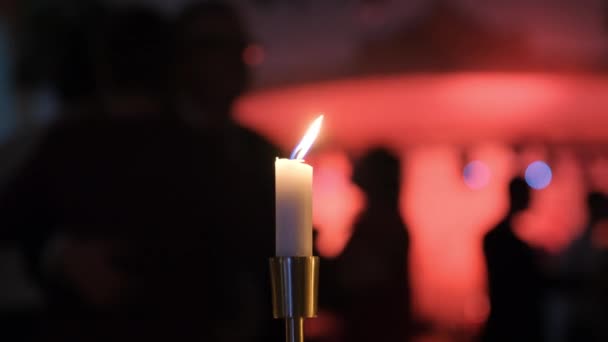 Bougies décoratives sur la table à manger, verres et bougies de Noël sur la table, bougies en cire blanche avec chandelier, restaurant, intérieur, silhouettes floues de danseurs . — Video