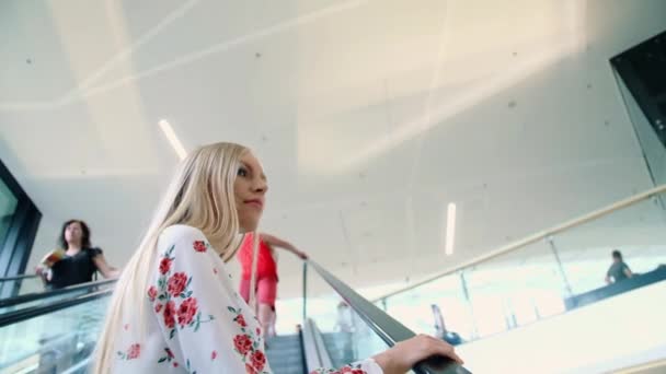 Jeune femme blonde chevauchant sur l'escalator . — Video