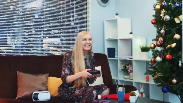 Medium close up of nice girl playing on playstation near the Christmas tree — Stock Video