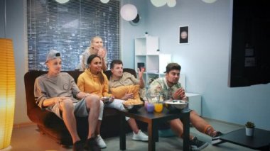 Heyecanlı taraftarlar TV 'de maç izliyor ve takım sayı yaptığında patlamış mısır döküyorlar.