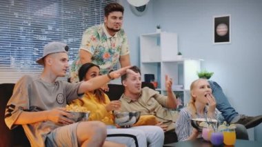 Evde aperatifler yerken Tv'de spor izleyen çok ırklı yound insanlar