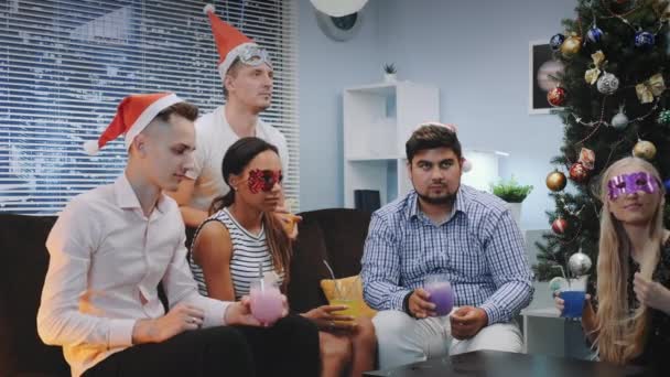 Multinationale jeugd in Santa hoeden en feest maskers het maken van Cheers op Kerstmis — Stockvideo