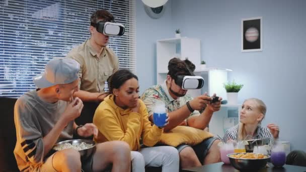 Två unga män spelar online-spel i virtual reality glasögon, en kille vinner slaget — Stockvideo