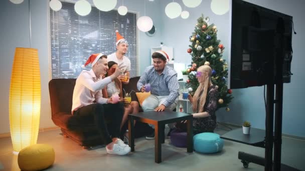 Ευτυχισμένα αγόρια και κορίτσια στο Σάντα καπέλα και μάσκες πάρτι που κάνουν επευφημίες τα Χριστούγεννα — Αρχείο Βίντεο