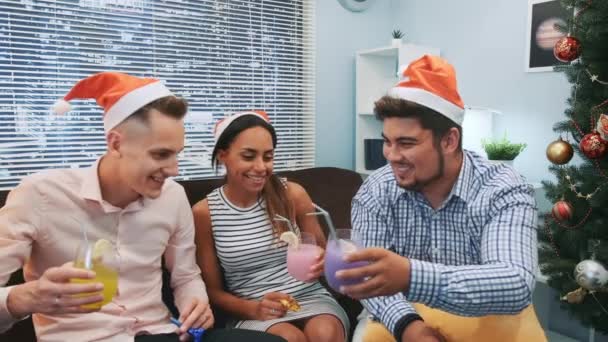 Close up de dois meninos e uma menina em chapéus de Papai Noel fazendo vivas e soprando apitos festa — Vídeo de Stock