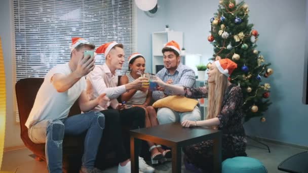Wesoła przyjaciele w Santa kapelusze podejmowania rozmów wideo przez smartphone na imprezę Świąteczna — Wideo stockowe