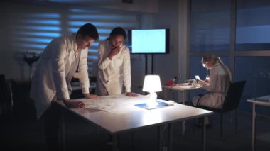 Çoklu Irklı Elektronik Geliştirme Mühendisleri laboratuvarda kontrol elektroniği şemasını tartışıyor