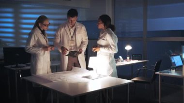 Teknoloji Araştırma Tesisi: Beyaz önlüklü çok ırklı Elektronik Geliştirme Mühendisleri anakart ve kontrol elektronik şeması ile laboratuvarda çalışıyorlar