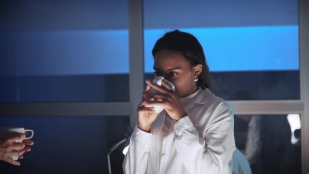 Close up of african american female engineer discussing something with cup of drink in lab — Stock Video