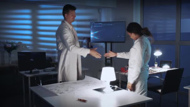 Двоє різноманітних вчених дарують вітання на зустрічі в лабораторії — стокове відео