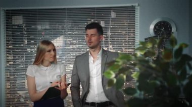 İş arkadaşı kağıt üzerinde notlar yaparken video projesi hakkında açıklamalar veren baş video editörü