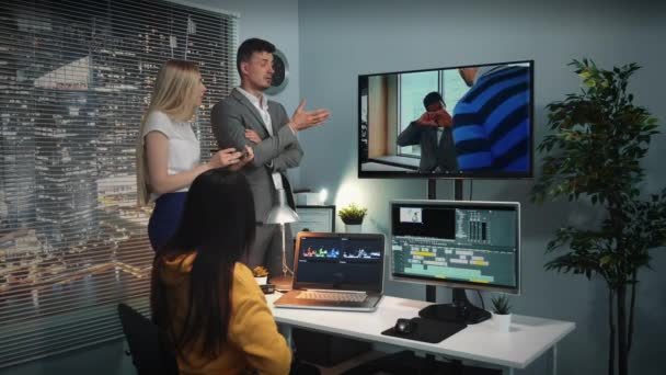 Equipo mixto de editores de vídeo escuchando a los principales comentaristas de vídeo visto en la pantalla grande — Vídeo de stock