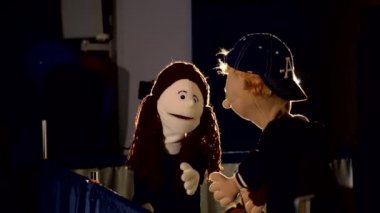 Kukla kız gösteri sırasında kukla çocukla konuşuyor.