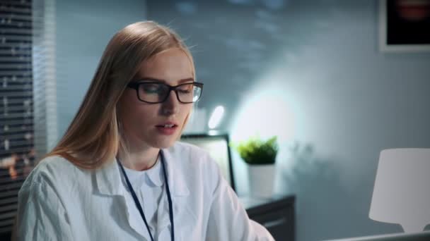 Крупним планом жіночий психолог в окулярах і лабораторному пальто робить відеодзвінок з пацієнтом — стокове відео