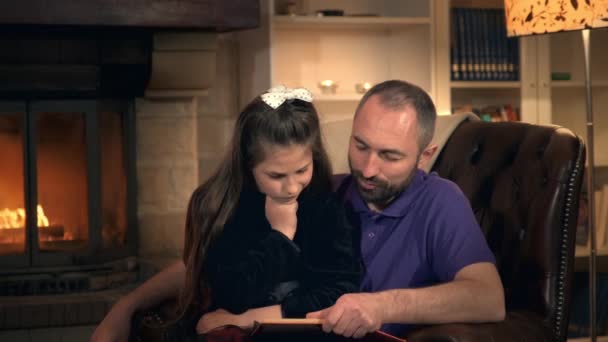 Papa lisant à sa petite princesse un conte de fées près de la cheminée le soir — Video