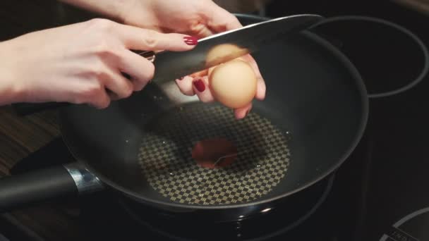 Разбивание яйца ножом и жарка на сковороде — стоковое видео