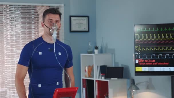 Fit atlet dalam masker oksigen berjalan di treadmill dengan elektroda terhubung pada dirinya — Stok Video