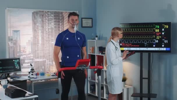 Herz-Atemtest: Kardiologe mit Tablet überwacht Sportler ekg — Stockvideo