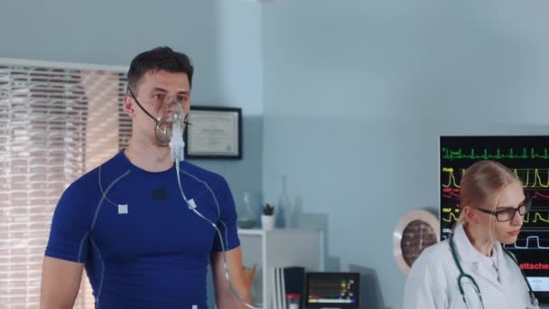 Primer plano medio del hombre en forma en la máscara de oxígeno caminando en la cinta de correr en el laboratorio de deportes científicos — Vídeos de Stock