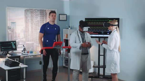 Pendant le test sur tapis roulant, deux médecins de course mixte en lunettes VR parlent de quelque chose — Video