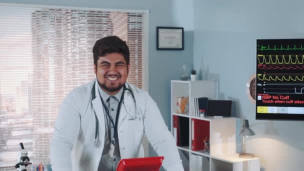 Close-up de mestiço sorrindo médico em jaleco andando na esteira — Vídeo de Stock