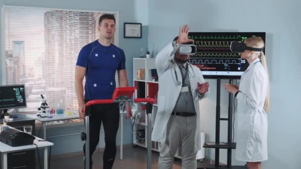 Médecins multiraciaux en lunettes de réalité virtuelle parlant de quelque chose et gestualisant pendant le stress test — Video