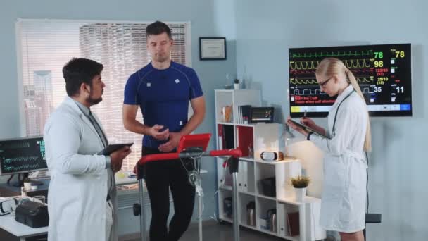 Mieszany naukowiec sportowy, który wyjaśnia sportowcom dane EKG podczas testów na bieżni — Wideo stockowe