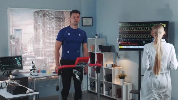 Female cardiologist coming to examine athlete stress testing on treadmill — Stock Video