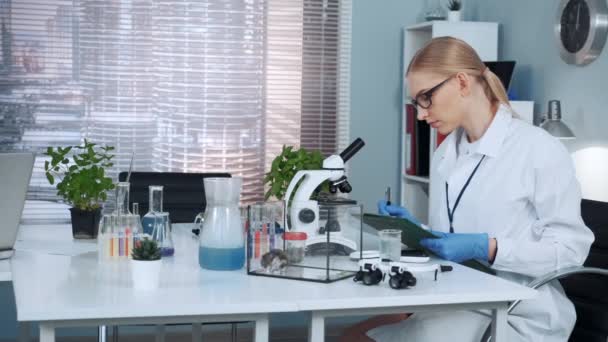 Smart female chemistry scientist in lab coat writing the results of the experiment — Stock Video