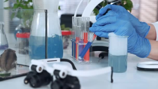 Close-up of scientist hands in lab gloves mixing compounds in test tube with use of pipette — Stock Video