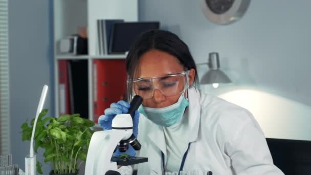 Крупный план чернокожей женщины-ученого был поражен результатом эксперимента под микроскопом — стоковое видео
